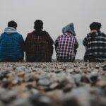 un gruppo di ragazzi di spalle guarda il mare, in un tempo sospeso, con la paura del fallimento