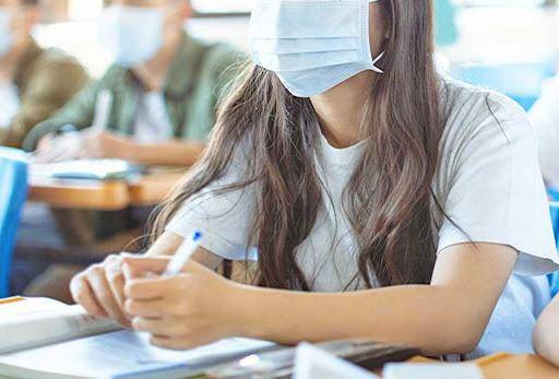 bambina con la mascherina sul banco di scuola