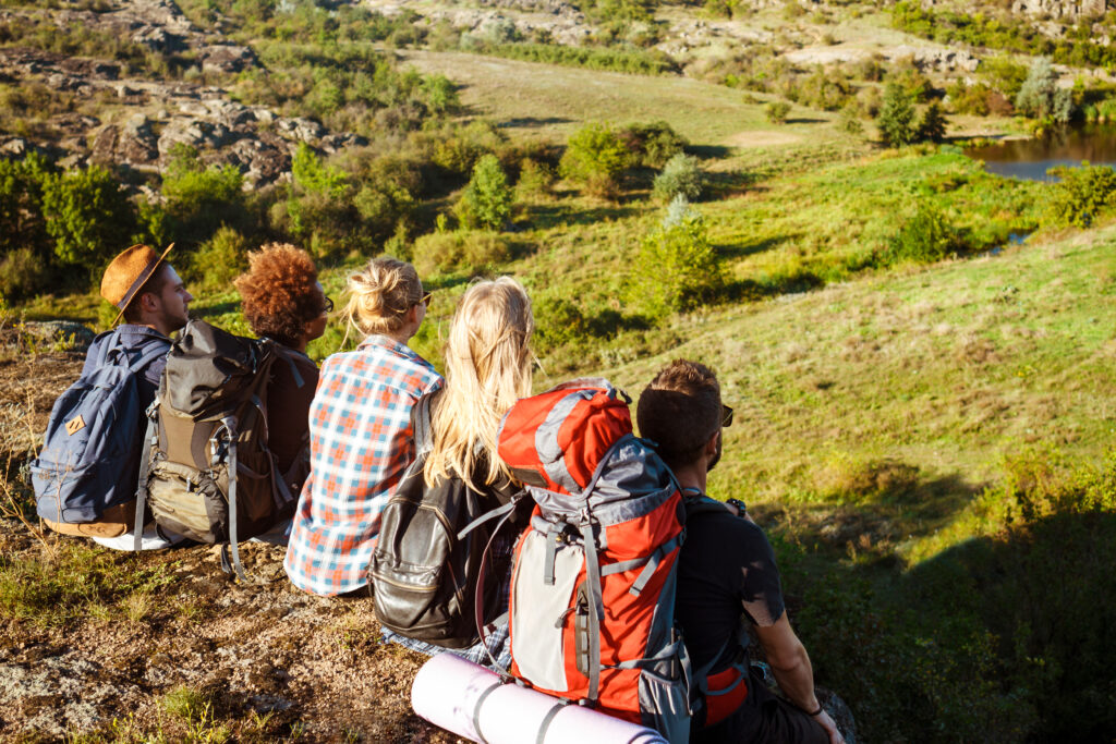 Young friends travelers sitting on rock in canyon, enjoying view.